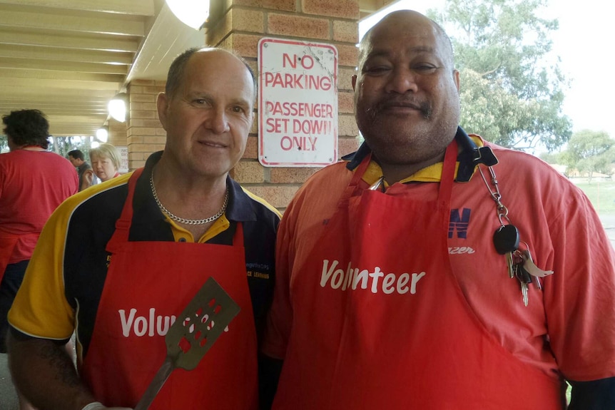 Wongutha  Aboriginal School staff Wayne Royan and Digby Holeong pose for a photo wearing barbeque aprons.
