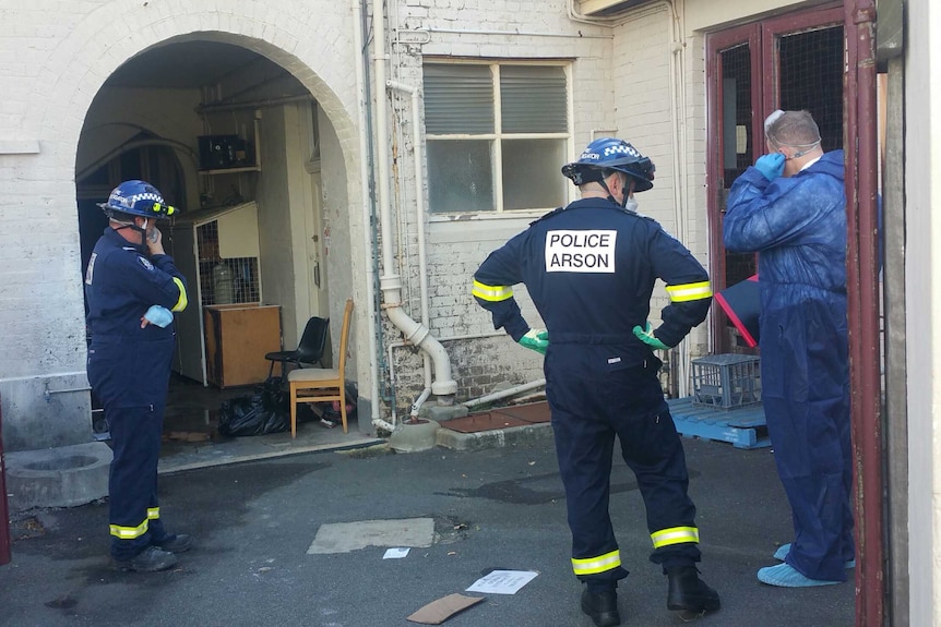 Arson squad investigators probe the scene of a fire at Albany's historic Premier Hotel.