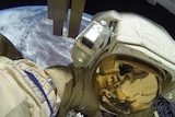 a close up image of Dmitry Petelin in his cosmonaut space suit taking a walk outside the ISS