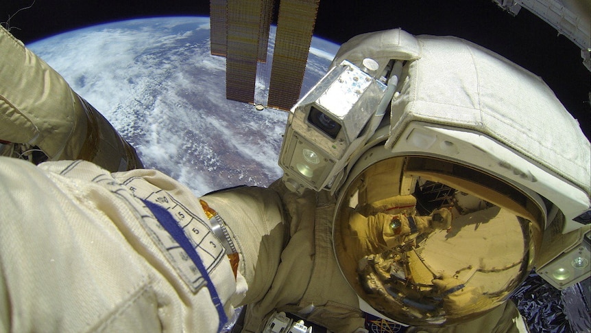 a close up image of Dmitry Petelin in his cosmonaut space suit taking a walk outside the ISS