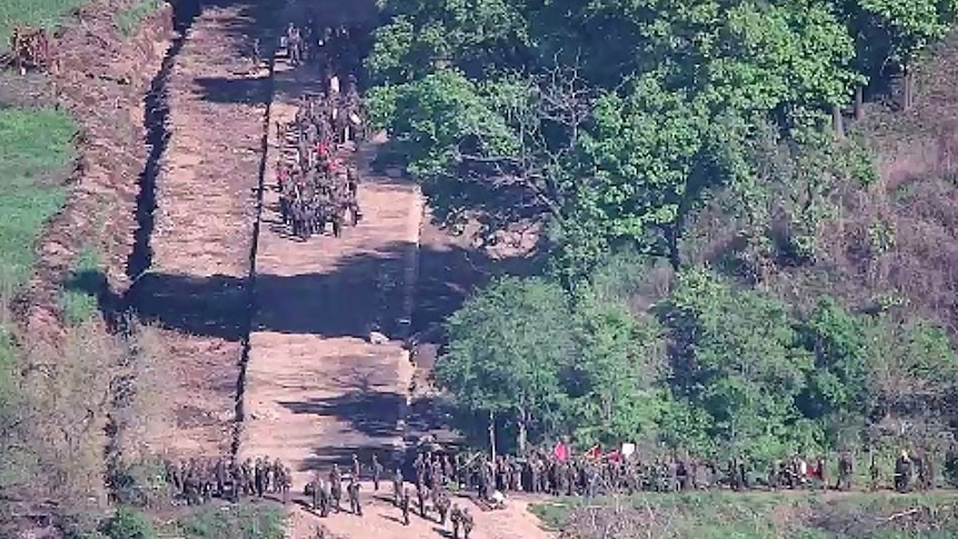 Soldiers march towards other troops in a line.