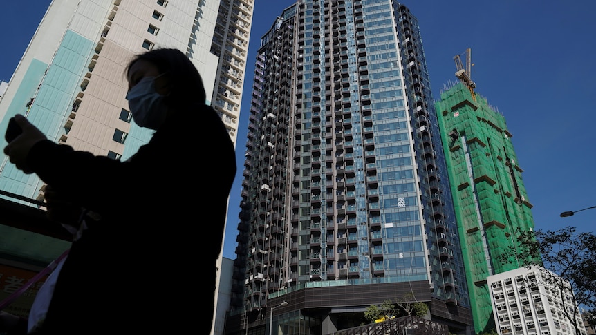 A pedestrian walks past a residential development in Hong Kong.