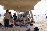 Beach-goers huddle under a jetty