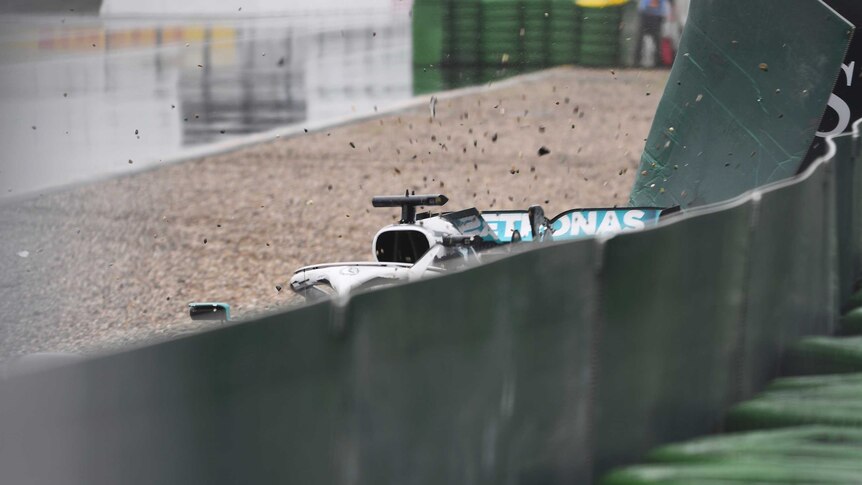 Debris flies in the air as a Formula One car crashes into a holding fence during a grand prix.