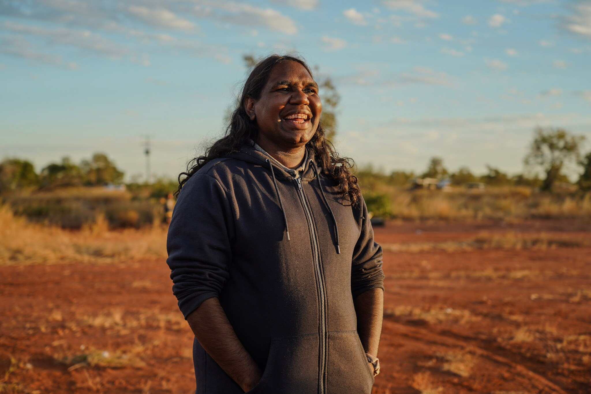 Woman in hoodie standing against red dirt