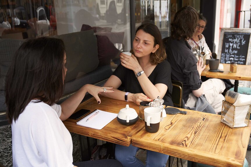 Two women chat over tea at a cafe
