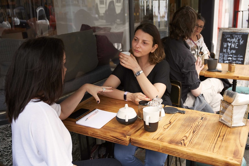 Two women chat over tea at a cafe