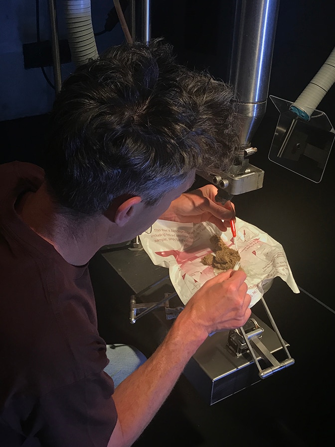 Ryk Goddard takes a sample from the discharge of MONA's Cloaca Professional art installation by Wim Delvoye.