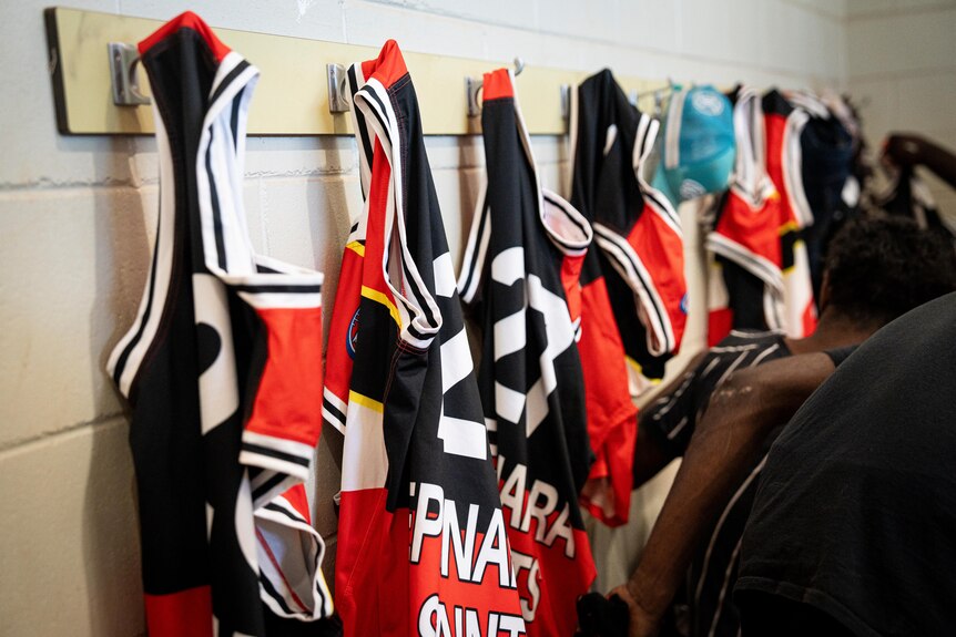 a photo showing a Epenarra Saints Jersey hanging on wall hooks