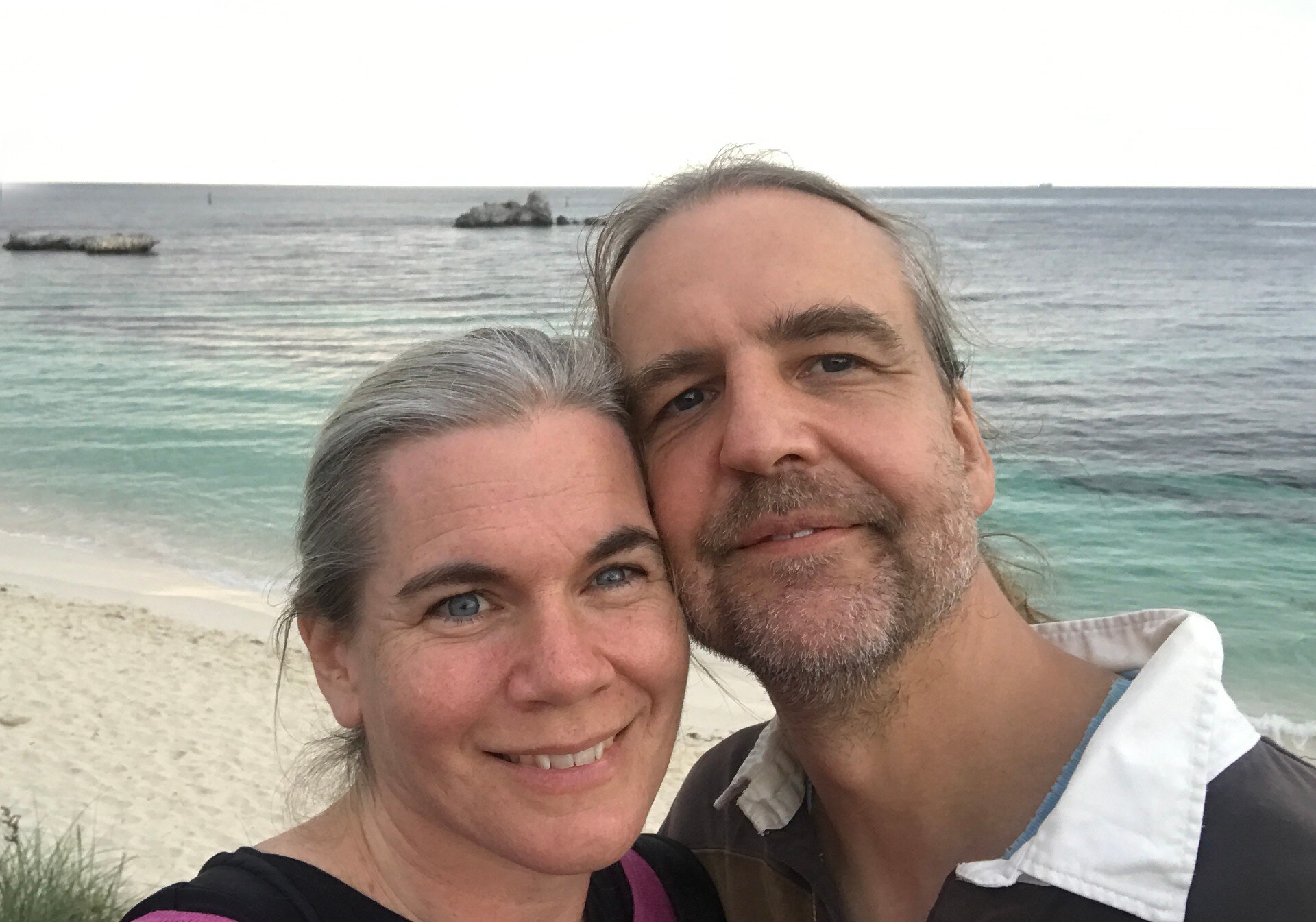 A middle-aged couple, Archa Fox and her husband Charlie Bond, posing on the beach