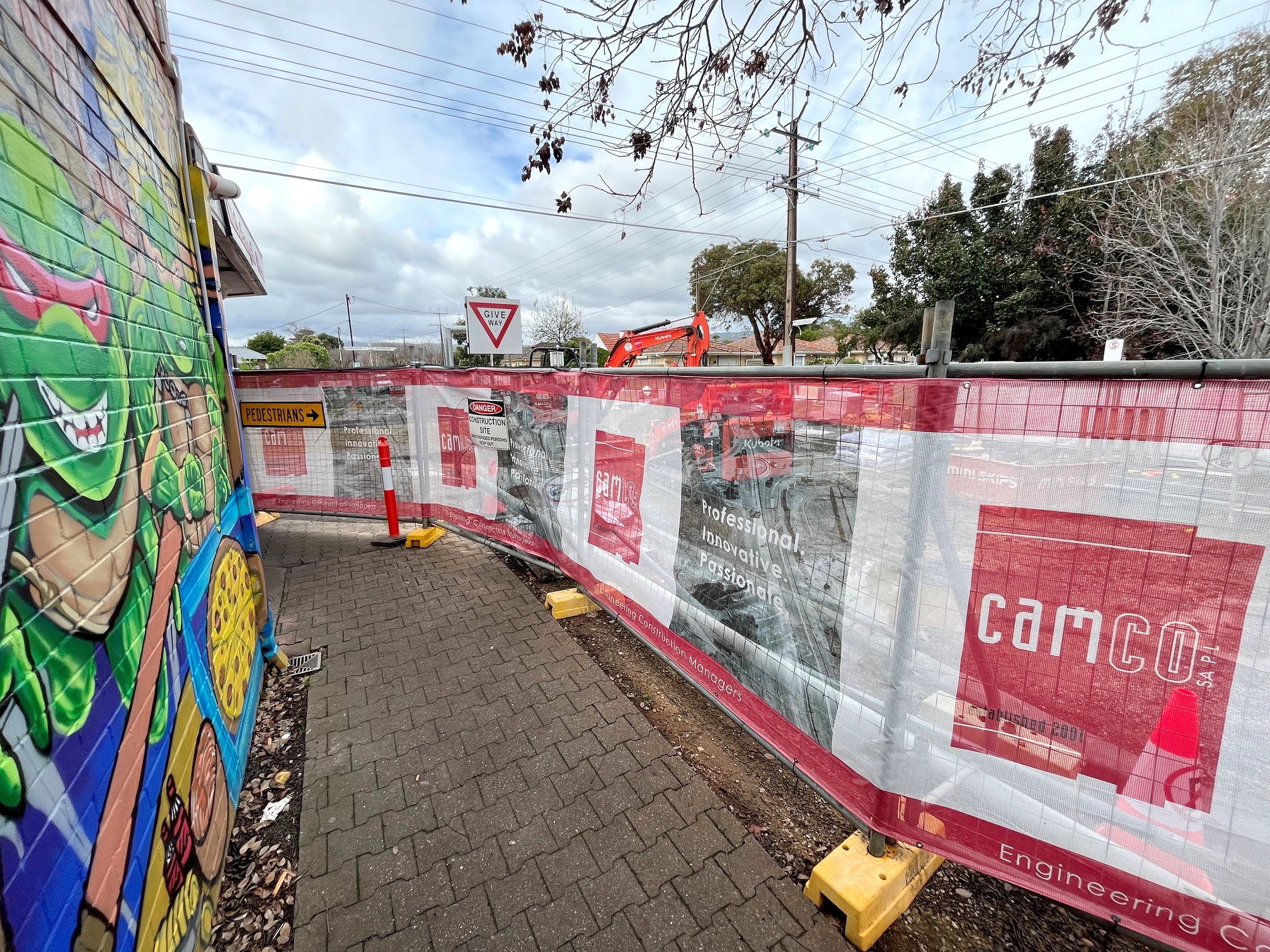 Strip fencing along a footpath next to a building's painted wall