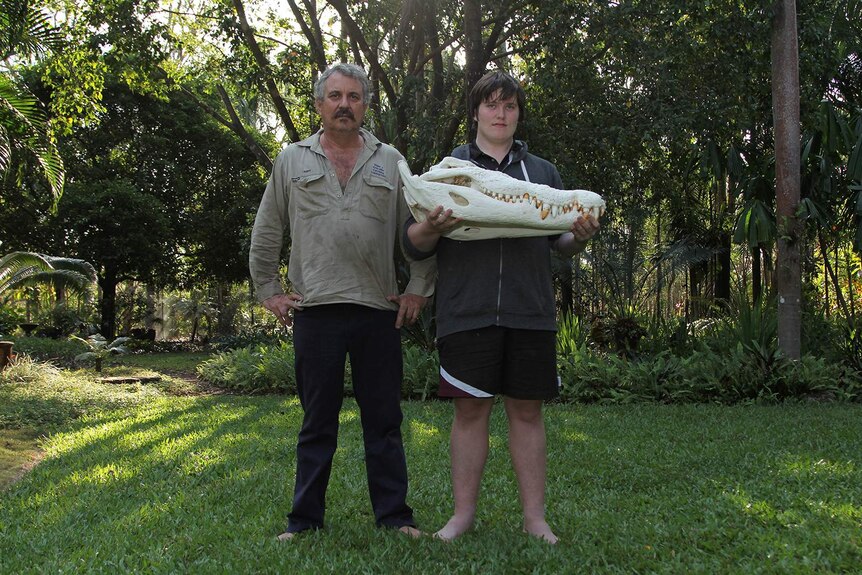 A photo of father and son Roger and Brody Matthews standings ide by side and holding a crocodile skull.