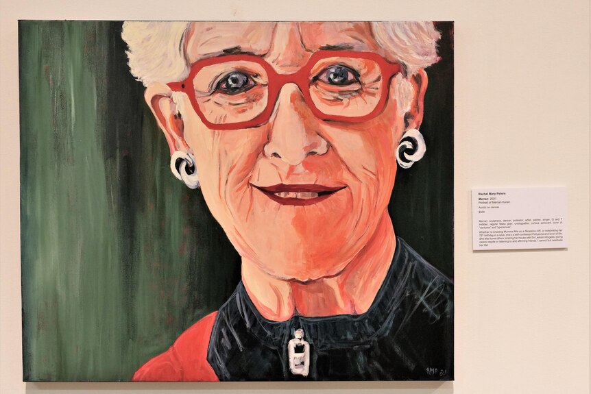 A portrait of Merran Koren wearing red framed glasses