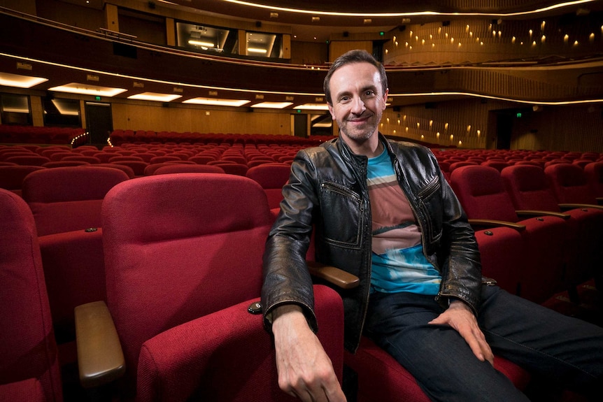 Mitchell Butel seated inside an empty theatre.
