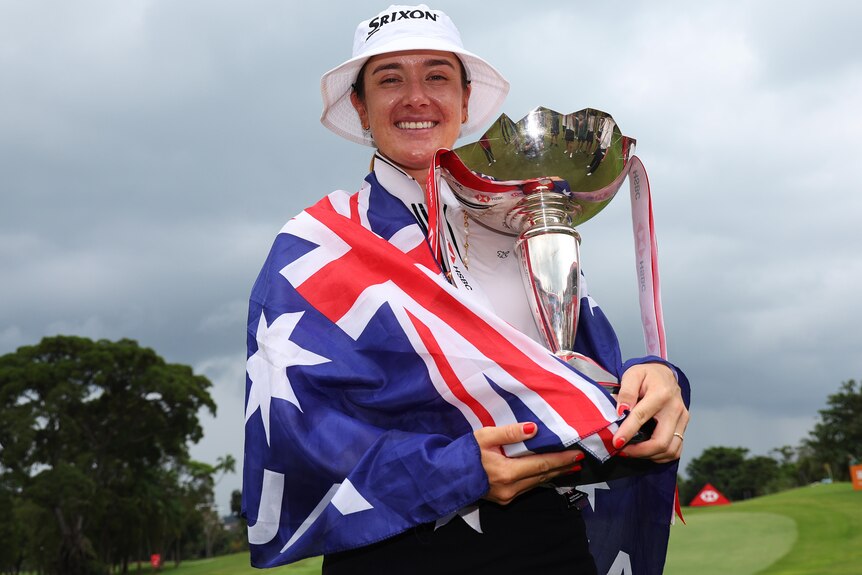 Hannah Green, with the Australian flag draped over her shoulders, holds the LPGA Tour Women's World Championship trophy.