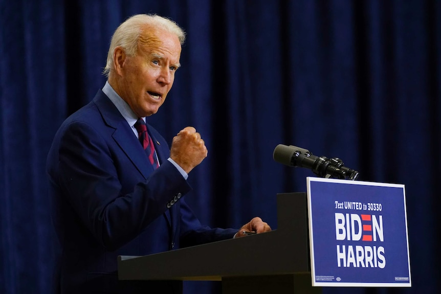 Joe Biden holds up a fist as he speaks from a podium.