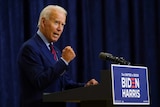 Joe Biden holds up a fist as he speaks from a podium.