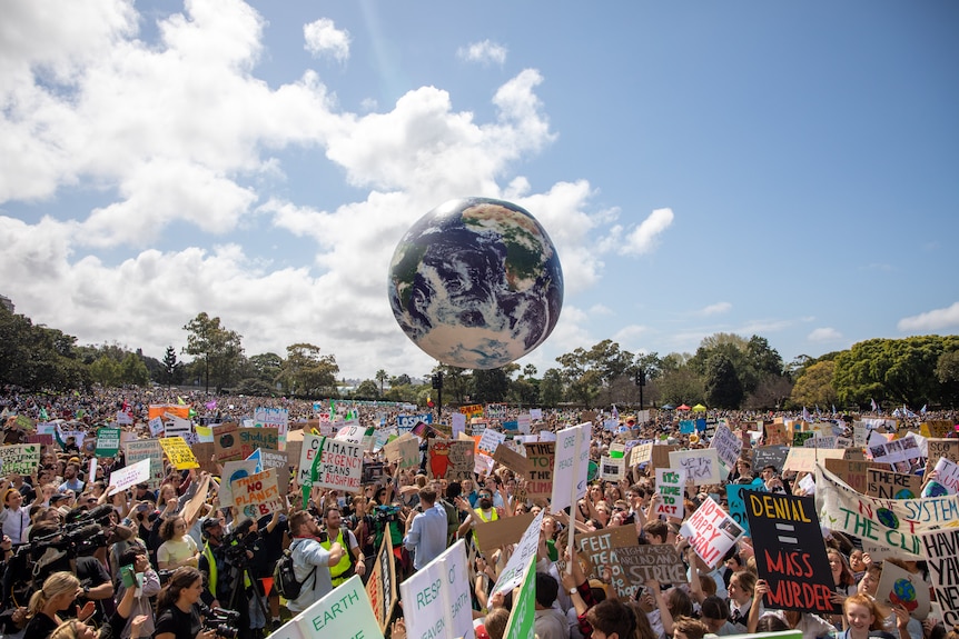 A massive inflated globe sits above a crowd of thousands at a climate change protest.