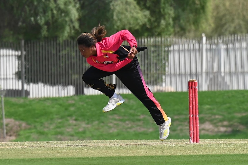 Una jugadora de bolos en pleno vuelo mientras juega a los bolos durante un partido de cricket.