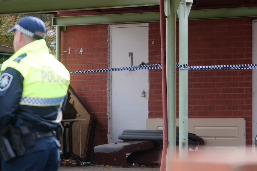 The worn front door of an apartment residence is marked off with police tape.