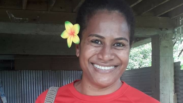 Woman in red T-shirt with flower behind right ear.