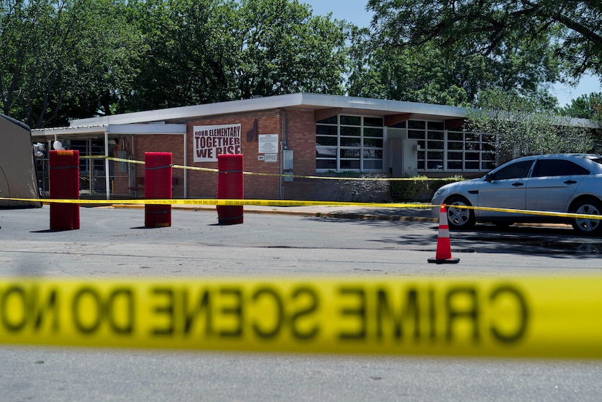 Crime scene tap around Robb Elementary School, a lowset brick building, after a shooting