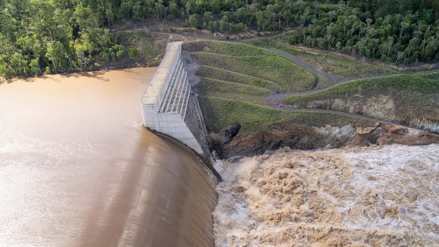 Brown flood water rushes over the spillway at Paradise Dam near Bundaberg