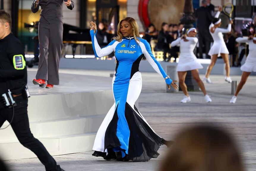 Serena Williams walks in a Paris runway show on the street in a blue athletic looking gown