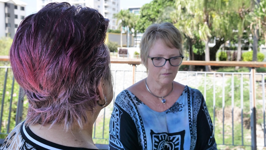 taken from behind one woman, the photo shows two women sitting in a park in a deep conversation