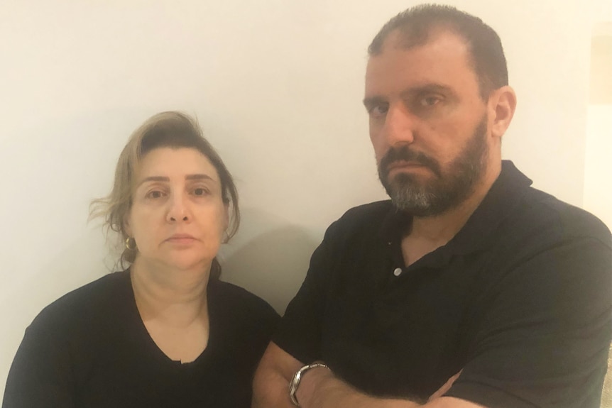 A man and woman wearing black shirts pose for a photo looking serious