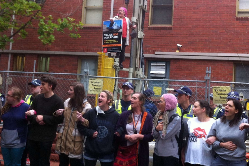 Protester Rosie  stands on top of drilling rig with East West Link protesters