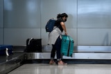 a woman picking up luggage at an airport