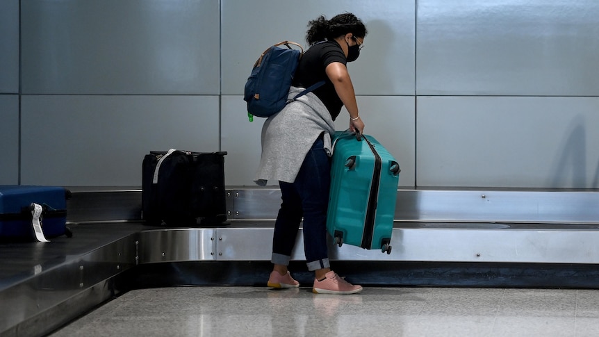 a woman picking up luggage at an airport