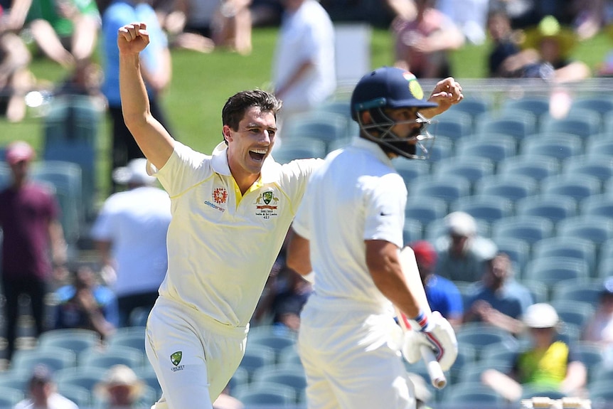 Pat Cummins runs past Virat Kohli who looks back over his shoulder