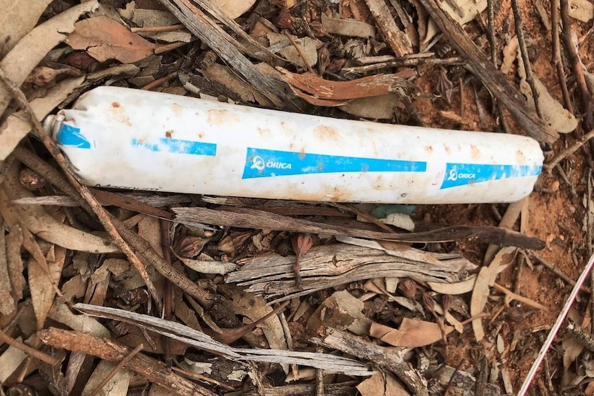 A white tube with blue writing on it lying in the bushland in Norseman Western Australia.