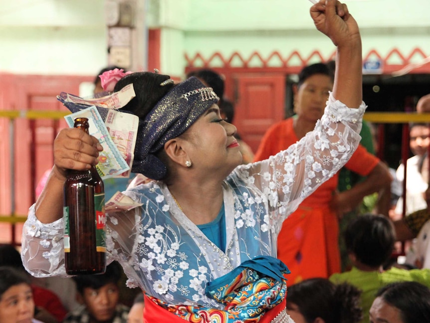 A woman smiles as she holds a beer and cigarette, while posing