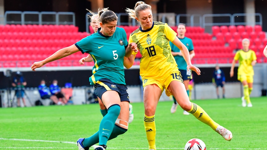 Two female soccer players contesting for the ball during a match