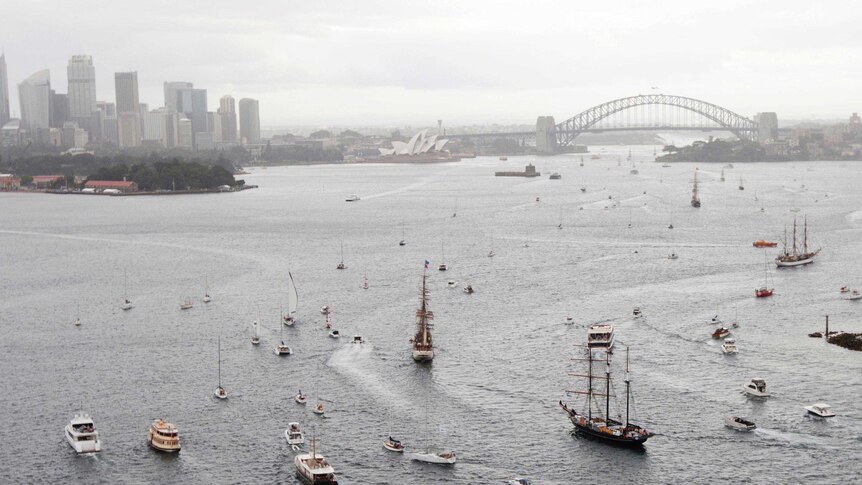 A fleet of tall ships moves through Sydney Harbour as part of the International Fleet Review.