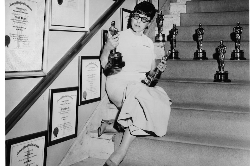 Edith Head sitting on the steps with her academy awards