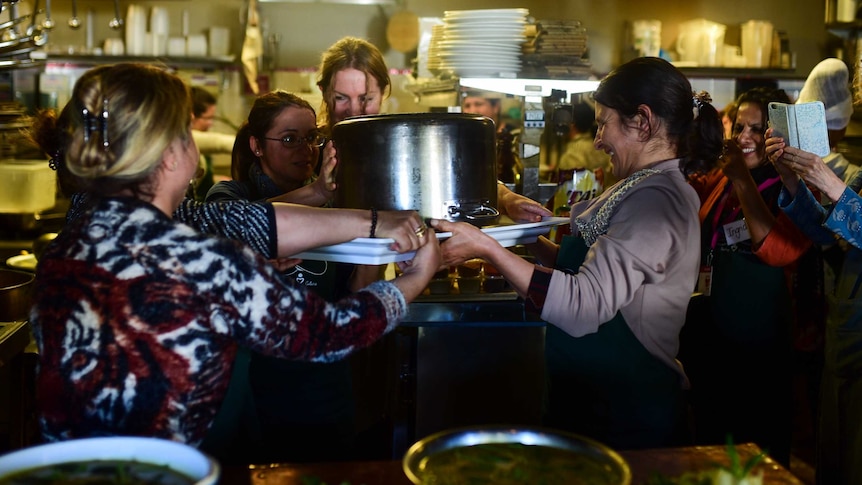 Women holding pot in kitchen