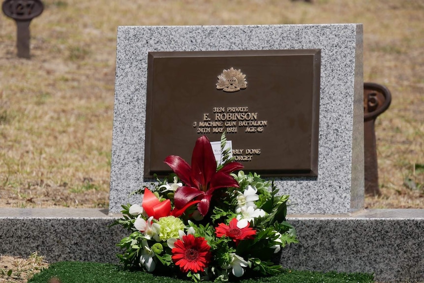 A floral wreath sits atop a headstone