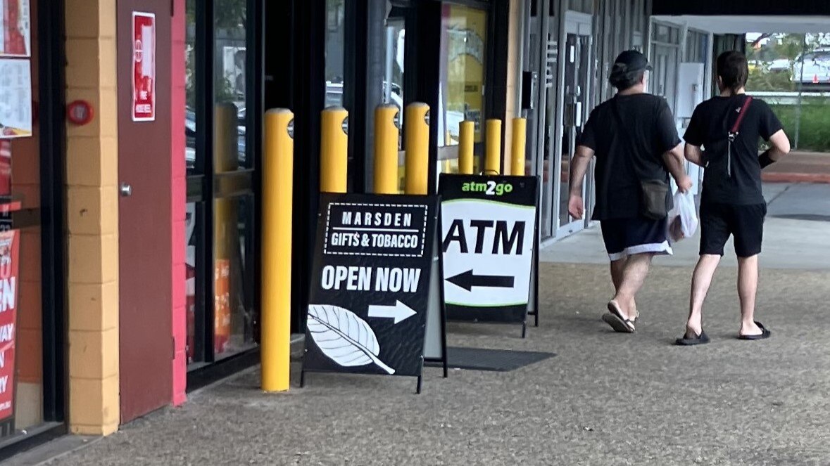 An open now sign next to a tobacco shop with an ATM sign advertised