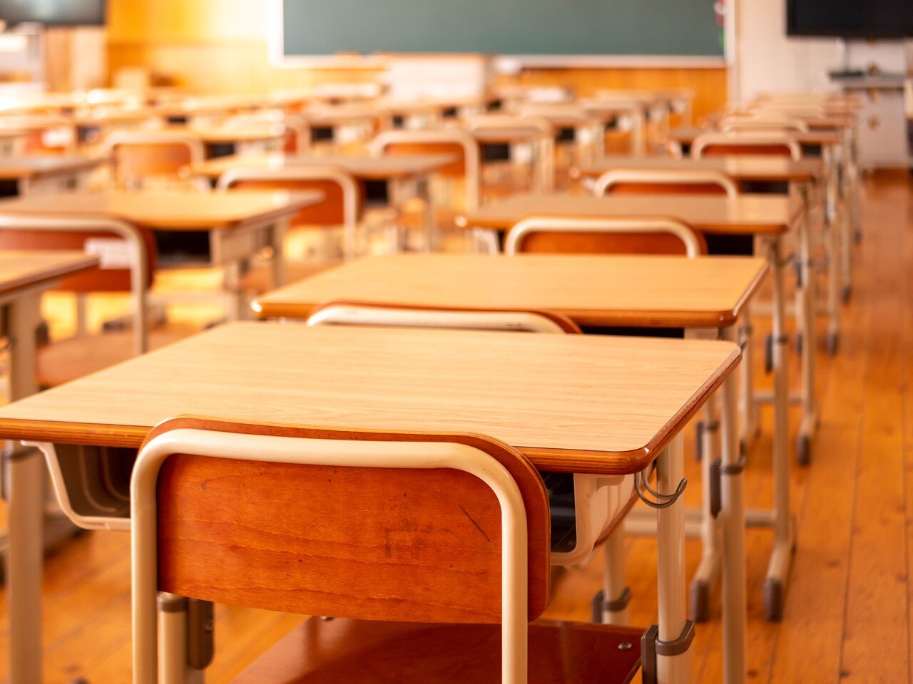 Rows of school desks with chairs and a blackboard