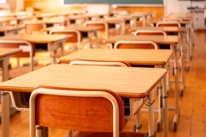 Rows of school desks with chairs and a blackboard