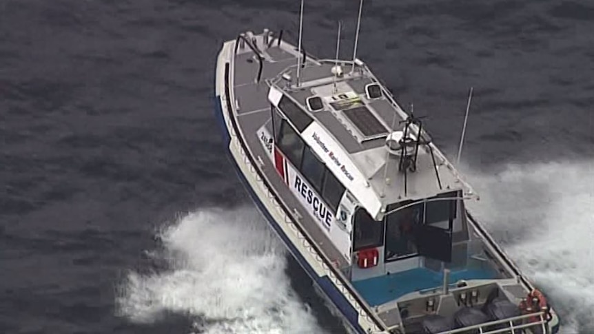 A Volunteer Marine Rescue boat on water. Spray splashes in its wake.