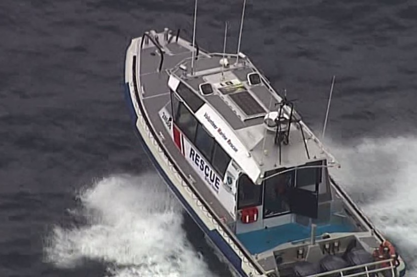 A Volunteer Marine Rescue boat on water. Spray splashes in its wake.