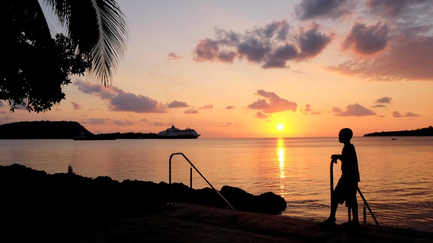 A unset image looking over the water, with a silhouette of a person looking at the view