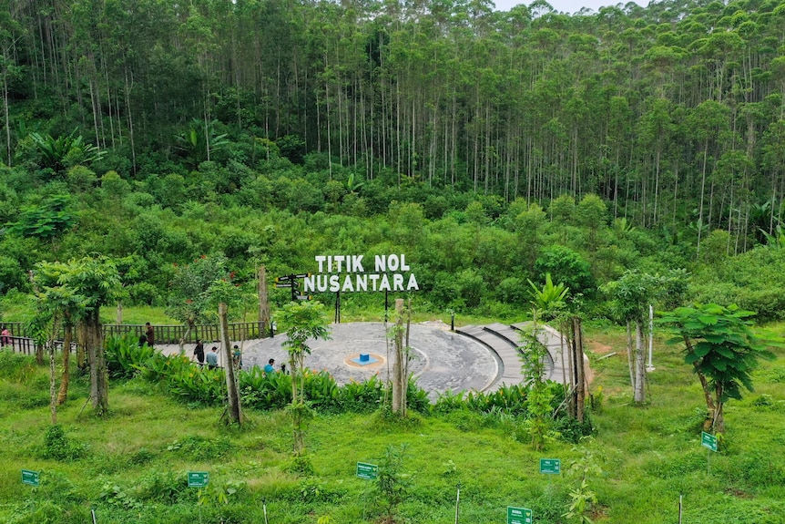 A sign read 'Titik Nol Nusantara' with green jungle behind it. 