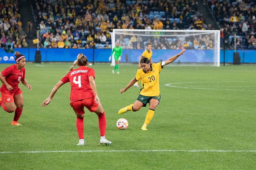 Sam Kerr lines up a shot on goal for the Matildas as two defenders watch on.