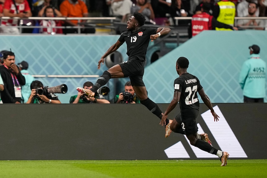 A Canadian soccer player leaps in the air in celebration after scoring a goal at the World Cup. 
